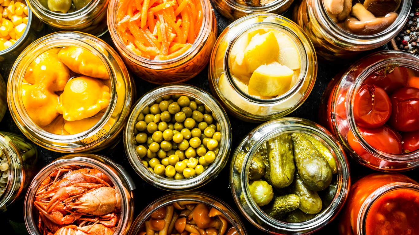 Banner do Portal É Vidro mostrando diversos alimentos e conservas em potes de vidro, como jarras de picles, pessogos em calda, pimentas e outros